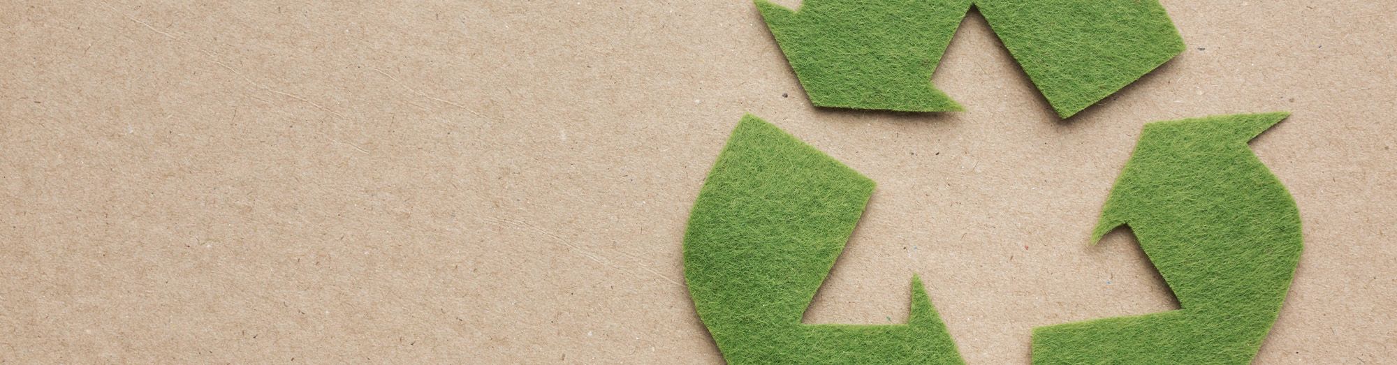 Recycling symbol, felt material on brown paper textured background.